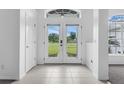 Bright foyer with double-door entry, tiled floors, and a view of the landscaped front yard at 15038 Willow Ln, Tavares, FL 32778