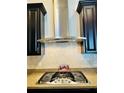 Close up of modern stainless steel range hood and cooktop with tile backsplash and granite countertops at 2051 Sandy Garden Ln, Winter Garden, FL 34787