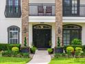 Up close view of the double door entry, landscaping, and balcony highlighting the home's curb appeal at 213 N Monterey Isle, Longwood, FL 32779