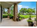 Covered front porch showcases brick columns, lush landscaping, and a glimpse of the well-kept front yard at 213 N Monterey Isle, Longwood, FL 32779