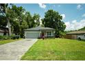 Single-story home with gray exterior, brick driveway, and green lawn at 309 E 13Th St, Apopka, FL 32703
