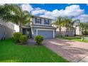 Charming two-story home featuring a well-manicured lawn, brick driveway, and inviting entrance framed by lush landscaping at 3943 Crawley Down Loop, Sanford, FL 32773