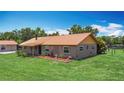 Exterior shot of brick home and separate structure with metal roofs and mature landscaping at 4160 Packard Avenue, St Cloud, FL 34772