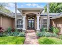 Welcoming front porch with columns, brick path, and manicured flower beds at 831 Royalwood Ln, Oviedo, FL 32765