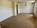 Spacious living room featuring neutral carpeting, a modern chandelier, and ample natural light from a window at 1050 Reading Ct, Winter Park, FL 32792