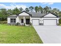 Beautiful one-story home with a two-car garage, well-manicured lawn, and modern design elements at 136 N James Pl, Groveland, FL 34736