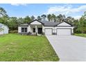 Attractive single-story home with a long driveway, two-car garage, and a lush green lawn at 136 N James Pl, Groveland, FL 34736