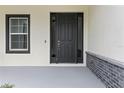 Close-up of the front door showcasing its contemporary design, sidelights, and surrounding architectural details at 136 N James Pl, Groveland, FL 34736