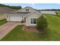 Single story stucco home featuring a well-manicured lawn and landscaping, including a picturesque lake view at 2400 Addison Creek Dr, Kissimmee, FL 34758