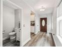 Inviting entryway with wood-look flooring, a decorative light fixture, and a conveniently located half bathroom at 2777 Monticello Way, Kissimmee, FL 34741