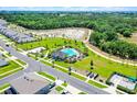 Aerial view of a modern residential neighborhood with community pool, sidewalks and natural backdrop at 4413 Lions Gate Ave, Clermont, FL 34711