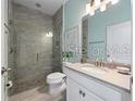 Modern bathroom featuring a walk-in shower with tile surround, and a vanity with a light-colored countertop at 4413 Lions Gate Ave, Clermont, FL 34711