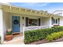 Close-up of a cozy front porch with a light blue door, decorative wreath, and charming landscaping at 609 Langholm Dr, Winter Park, FL 32789