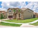 Well-manicured lawn complements this home's stone facade and neutral siding, set in a tranquil neighborhood at 8801 Corcovado Dr, Kissimmee, FL 34747