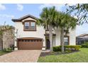 Beautiful two-story home with a well-maintained lawn, mature landscaping, and a brick driveway at 8801 Macapa Dr, Kissimmee, FL 34747