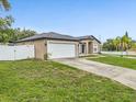 Single-story home features a two-car garage, well-manicured lawn, and a classic facade under a clear blue sky at 112 Lake Butler Ave, Haines City, FL 33844