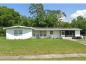 An exterior shot of a charming one-story home with a screened-in porch and a well-maintained lawn at 115 Lake Dot Dr, Sanford, FL 32773