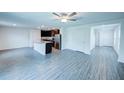 Open floor plan with wood-look floors, ceiling fan, and a kitchen area with stainless steel appliances at 1303 Congo Ct, Kissimmee, FL 34759