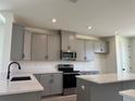 Modern kitchen with gray cabinets, stainless steel appliances and quartz countertops with black accents at 15107 Grove Lake Dr, Winter Garden, FL 34787