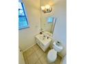 Clean half bathroom featuring a classic white vanity and toilet, illuminated by modern lighting at 312 Partridge Pea Ln, Ocoee, FL 34761