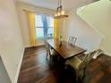 Bright dining room featuring hardwood floors, a modern light fixture, and large windows with yellow curtains at 312 Partridge Pea Ln, Ocoee, FL 34761