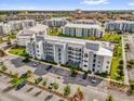 Aerial view of a modern apartment building with ample parking and beautifully landscaped grounds in a vibrant community setting at 3180 Paradox Cir # 304, Kissimmee, FL 34746