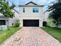 Modern two-story home with a dark garage door and a brick-paved driveway at 4900 Beach Blvd, Orlando, FL 32803