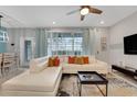 Bright living room featuring a white sectional, ceiling fan, and large windows offering plenty of natural light at 720 Gardenia Ln, Davenport, FL 33897
