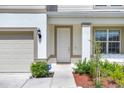 Close-up of the front door with an ADT security sign and a small garden bed with mulch and lush greenery at 7639 Agrigento St, Clermont, FL 34714