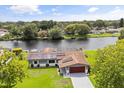 Aerial view of a home with a scenic waterfront view, solar panels, screened-in patio, and a lush green lawn at 930 Chickadee Dr, Port Orange, FL 32127