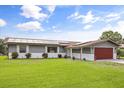 Charming single-story home with a well-manicured lawn, solar panels, and an attached two-car garage at 930 Chickadee Dr, Port Orange, FL 32127
