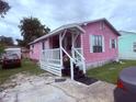 Cozy pink home featuring a covered front porch and a small yard with driveway at 1038 26Th St, Orlando, FL 32805