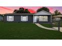 Charming single-story home with a gray exterior, white trim, and a well-maintained front yard at sunset at 325 Little Aspen Ct, Ocoee, FL 34761