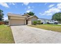 View of the home's front exterior with a large driveway, manicured lawn, and two-car garage at 399 Lake Daisy Dr, Winter Haven, FL 33884
