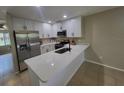 Modern kitchen featuring white cabinets, stainless steel appliances, and a quartz countertop bar at 4883 Cherokee Rose Dr, Orlando, FL 32808