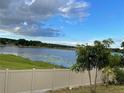 Scenic lake view from the backyard of the property with lush green grass and a privacy fence at 6569 Long Breeze N Rd, Orlando, FL 32810