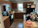 Functional kitchen with dark wood cabinets, black appliances, and laminate countertops at 7047 Sw 131St Loop, Ocala, FL 34473