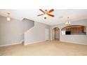 Cozy living room with carpet, ceiling fan, and an archway leading to the kitchen and other rooms at 9140 Grey Moss Dr, Orlando, FL 32832