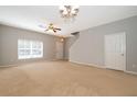 Bright living room featuring neutral walls, carpet, a ceiling fan, and a staircase to the upper level at 9140 Grey Moss Dr, Orlando, FL 32832