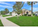 Landscaped front yard with a lush green lawn, mature trees, and a well-maintained exterior at 915 Lockbreeze Dr, Davenport, FL 33897
