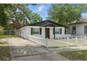 White bungalow with dark trim, complemented by a concrete driveway and a well maintained lawn at 1002 Cypress Ave, Sanford, FL 32771