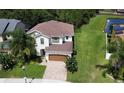 Aerial view of a well-maintained two-story home with lush green lawn and serene water view at 1016 Fountain Coin Loop, Orlando, FL 32828