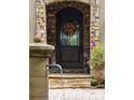 Close-up of the front door with stone archway, decorative wreath, and potted plants at 11106 Coniston Way, Windermere, FL 34786