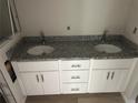 Bathroom vanity featuring double sinks, granite counters, and white cabinets at 14489 Se 38Th Ter, Summerfield, FL 34491