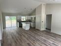 Spacious living area showcases an open kitchen with granite counters, white cabinetry, stainless faucet, and wood-look flooring at 14495 Se 38Th Ter, Summerfield, FL 34491