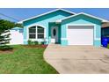 Brightly painted house features a well-maintained lawn and a driveway leading to a single-car garage at 1618 Oregon Ave, St Cloud, FL 34769