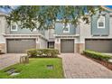 Townhouse exterior featuring gray stucco, brick driveway, and a beautiful shrub in front at 1852 Garden Sage Dr, Oviedo, FL 32765