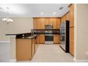 Kitchen with wood cabinets, granite countertops, stainless steel appliances, and tile flooring at 1852 Garden Sage Dr, Oviedo, FL 32765