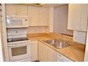Well-lit kitchen featuring sleek white appliances, ample cabinetry, and a stainless steel sink at 3012 S Semoran Blvd # S, Orlando, FL 32822