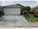 View of a single-Gathering home with a two-car garage and landscaped front yard at 5224 Florida Holly Dr, Orlando, FL 32811